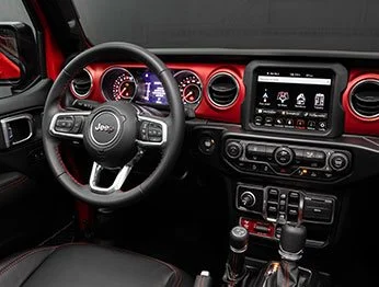 Interior do Jeep Gladiator com painel na cor vermelha e preta, câmbio automático de 8 marchas e central multimídia de 8,4 polegadas.