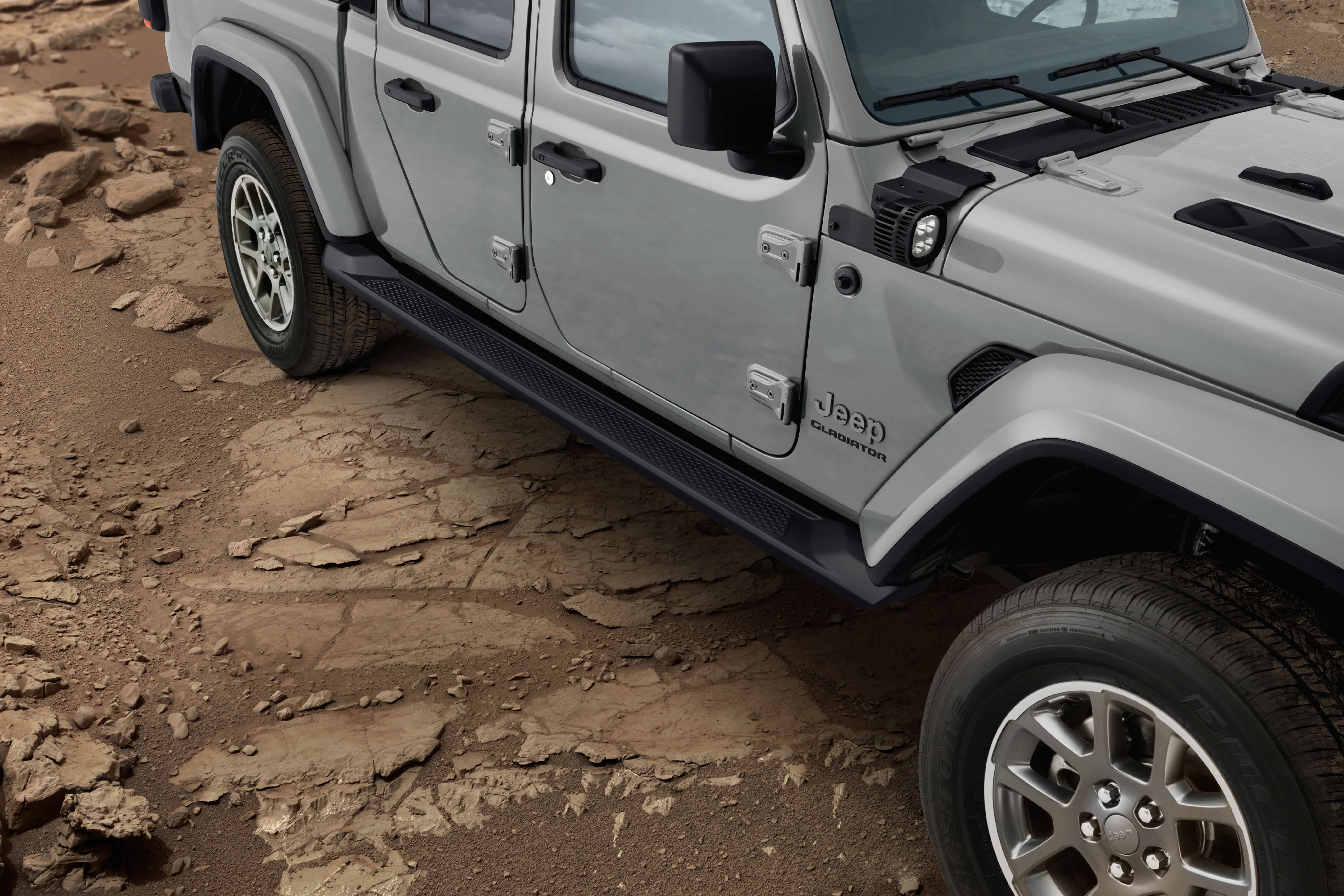 Detalhe da lateral do Jeep Gladiator em terreno arenoso, com destaque para o estribo lateral preto.