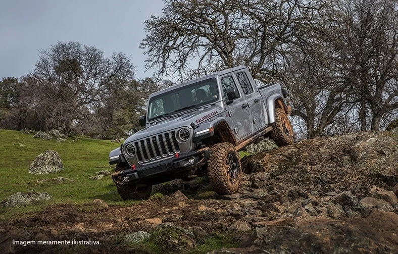 Jeep Gladiator em terreno acidentado com rochas e grama.